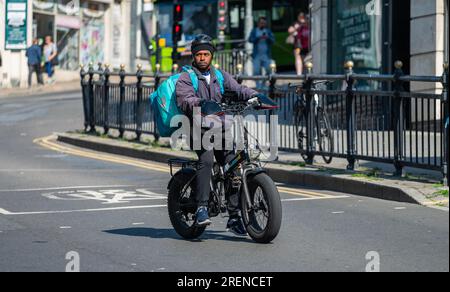 Radfahrer in einer Stadt fährt Fahrrad mit Deliveroo Food, online bestellt, UK. Stockfoto