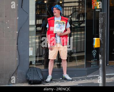 Ein Mann, der auf der Straße steht und das Big Issue Magazin in Brighton, Brighton & Hove, East Sussex, England, UK, verkauft. Stockfoto