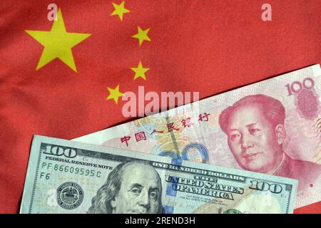 China. 29. Juli 2023. Auf diesem Foto sind einhundert US-Dollar- und einhundert Renminbi-Banknoten auf einem Tisch mit der chinesischen Flagge im Hintergrund dargestellt. Kredit: SOPA Images Limited/Alamy Live News Stockfoto