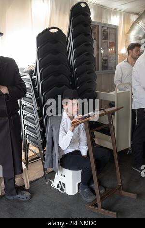 Bei Tisha B'AV Services beobachtet ein junger Mann die trauernden Aspekte des Tages, indem er fastet, auf einem niedrigen Sitz sitzt und keine Lederschuhe trägt. In Rockland. Stockfoto