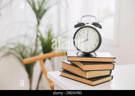 Alte Glockenuhr auf Stapel-Büchern, Zeiten zum Lernen Lesen Erziehung Erinnerungskonzept. Stockfoto