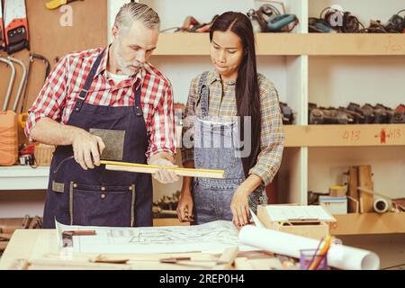 Cheffachmann, weiß, männlicher heimwerker, Holzarbeiten, reparieren Heimmöbel in der Werkstatt, Ehefrau hilft. Stockfoto