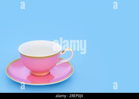 Teetasse aus rosafarbenem und goldenem Porzellan. Elegantes, luxuriöses Trinkset auf babyblauem Pastellhintergrund mit Kopierbereich. Minimale Zen-Komposition. Stockfoto