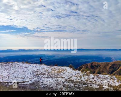 Atemberaubende Landschaft: Eine Person, die das riesige schneebedeckte Doon Valley inmitten des Winters in Mussoorie, Indien, bestaunt. Fesselnder Blick auf den Winter Stockfoto