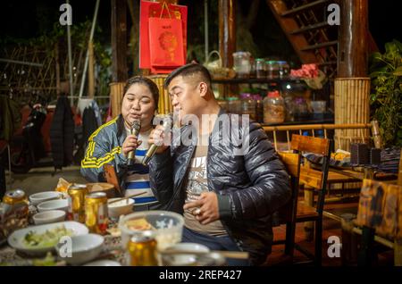 Ein weißes thailändisches ethnisches Minderheitenpaar singt nach dem Abendessen in seiner Gastfamilie in Mai Chau, Vietnam, zusammen Karokellieder. Stockfoto