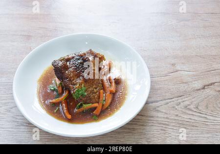 Gedünstetes Hähnchenschenkel und Bein mit Karotten in Sojasoße auf dem Teller Stockfoto