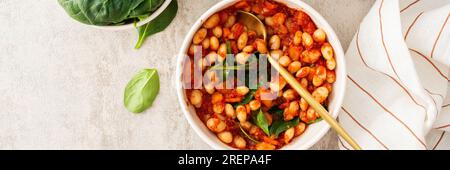 Gesundes Frühstück und Mittagessen Banner, gedünstete weiße Bohnen mit Karotten, Zwiebeln und Tomaten mit Spinatblättern, eine Schüssel Bohnen und Spinat Stockfoto