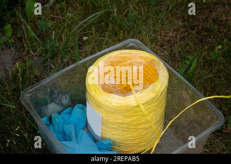 Blaue Gartengummihandschuhe mit gelber Jute in einem Behälter Stockfoto