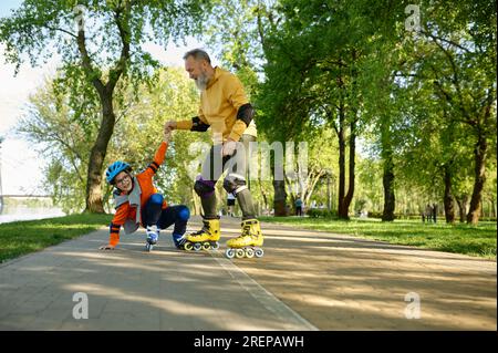 Ein Senior Rollschuh mit einem kleinen Jungen im Stadtpark Stockfoto