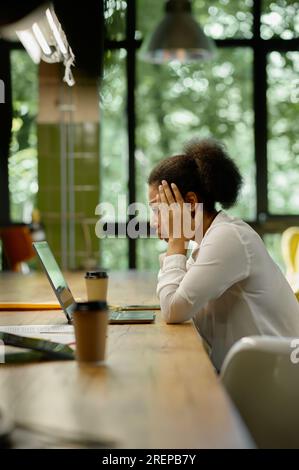 Schockierte, besorgte Geschäftsfrau, die sich im Büro ein Notebook ansah Stockfoto