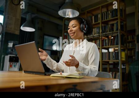 Büroangestellte mit Kopfhörern, die an einem Laptop arbeiten Stockfoto