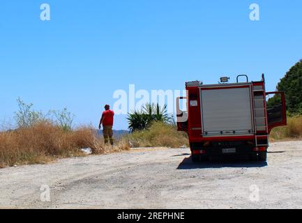 Griechischer Feuerwehrmann auf der Suche nach neuen Waldbränden von der Bergspitze in Troumpeta, Korfu Stockfoto