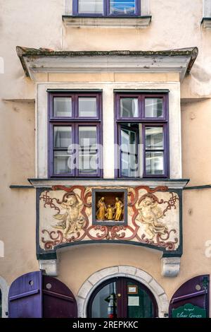 Goldene Statuen von Maria, Josef und Jesus in einer Nische mit Cherubs an der Fassade eines historischen Wiener Gebäudes Stockfoto