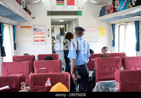 KENIA, Madaraka Expresszug von Nairobi nach Mombasa, die Eisenbahnstrecke wurde finanziert und gebaut von China, bewaffneten Polizisten / KENIA, Nairobi, Madaraka Express Zug von Nairobi nach Mombasa, die Bahnlinie wurde von China Road and Bridge Corporation CRBC gebaut und von der chinesischen EXIM Export-Import-Bank finanziert, bewaffnete Polizei Patrouille Stockfoto