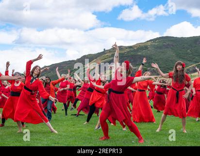 Edinburgh, Schottland, Großbritannien. 29. Juli 2023 Dutzende Frauen in roten Kleidern treffen sich im Holyrood Park, um zu tanzen und den alljährlichen „Most Wuthering Heights Day“ zu feiern – eine Hommage an die Musik von Kate Bush. Iain Masterton/Alamy Live News Stockfoto