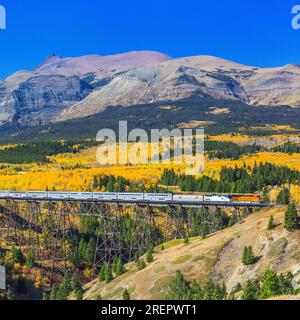 Personenzug überqueren Bock im Herbst unter Gipfel der Glacier-Nationalpark in der Nähe von East Glacier Park, montana Stockfoto