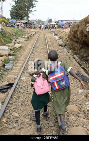 KENIA, Nairobi, Slum Kibera, Schüler mit Tornister, die von der Schule nach Hause laufen auf der Kibera Eisenbahnstrecke / KENIA, Nairobi, Slum Kibera, Kinder gehen nach der Schule nach Hause an der Kibera Bahnlinie Stockfoto