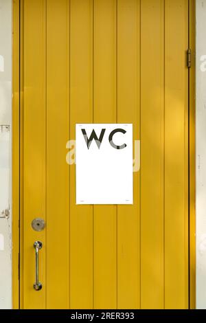 WC-Schild an einer gelben Holztür mit Kopierbereich Stockfoto