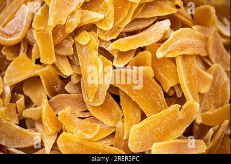 Getrocknete Mangoscheiben als Hintergrund. Kandierte Früchte, Mangostücke. Hintergrund von orangefarbenen getrockneten Mangos mit Textureffekt Haufen kandierter Scheiben, cryst Stockfoto
