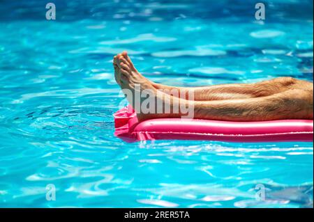 Sommerferienkonzept. Entspannender Mann im Pool. männersonnenbaden auf aufblasbarer Matratze in einem Swimmingpool Stockfoto