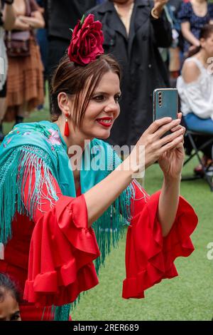 Feria de Londres, Wembley Park, Großbritannien. 29. Juli 2023 Feria De Londres, die größte Feier der spanischen Kultur Großbritanniens, bietet zum ersten Mal ein kostenloses 2-tägiges Festival im Wembley Park. Eine Dame in traditionellem spanischen Kleid filmt die Festlichkeiten auf ihrem Handy. Foto: Amanda Rose/Alamy Live News Stockfoto