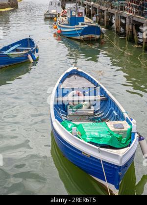 Einige Boote liegen in der Nähe eines hölzernen Anlegesteges. Seilwege im Wasser und die Boote spiegeln sich im Wasser wider. Stockfoto