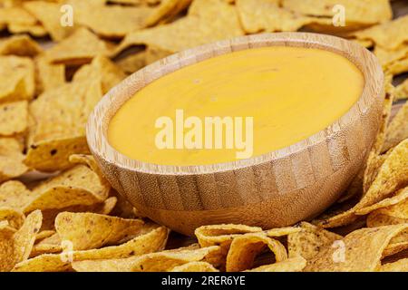Eine große Holzschüssel mit köstlichem Käsedip und gerösteten Maistortilla oder Nacho-Chips auf Holzhintergrund mit Kopierbereich Stockfoto