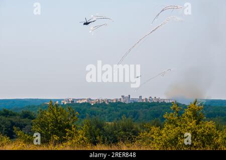 Militärhubschrauber, die sich der Luftverteidigung entziehen. Ein Helikopter setzt Hitzefallen frei, um einer Luftabwehrrakete zu entkommen. Militärluftfahrt auf einer Kampfsorte Stockfoto