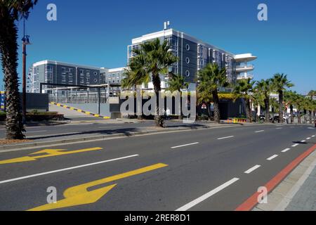 Hauptstraße mit gelber Markierung als Straßenschild, die in der Nähe des Hafenviertels mit modernen Gebäuden vorbeiführt. Stockfoto