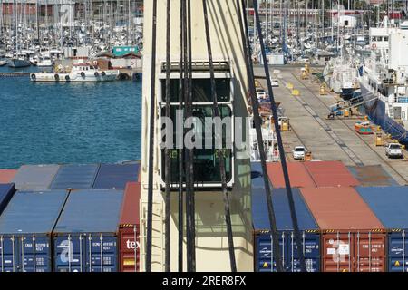 Direkter Blick auf die Kabine des Schiffskrans hinter dem geschmierten Stahldraht des beladenen Containerschiffs im Hafen. Stockfoto