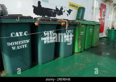 Grüne Kunststoffmülleimer für Haushaltsabfälle der Kategorie C, fest am Geländer befestigt. Stockfoto