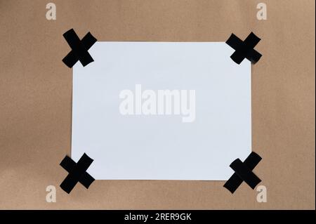 Leeres weißes Blatt auf braunem Hintergrund in Nahansicht geklebt Stockfoto