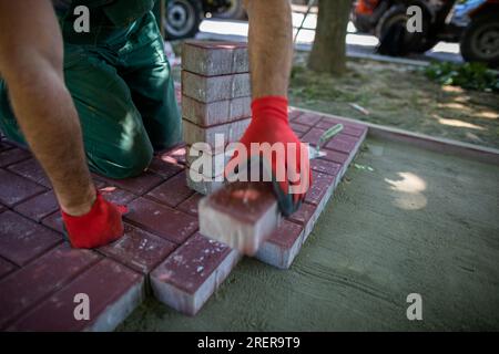 Im Sommer werden Straßenbauarbeiten zum Verlegen eines neuen Fußgängerwegs durchgeführt. Stockfoto