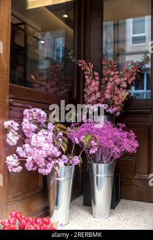 Verschiedene Farben in der Nähe des Blumenladens in London. Große Blumensträuße in Zinnvasen in Blau- und Violetttönen Stockfoto