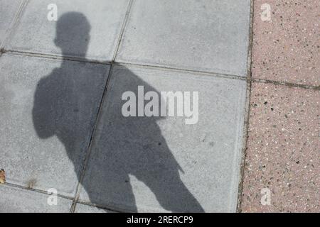 Ein Foto des Schattens eines Jungen auf einem Bürgersteig. Stockfoto
