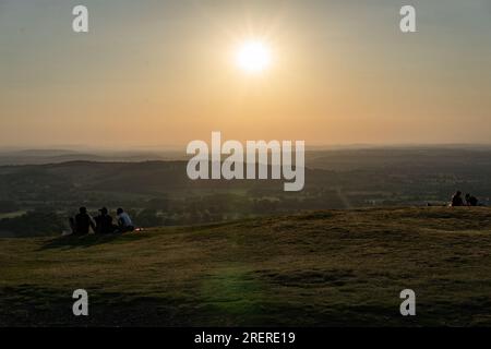 Eine Gruppe von Menschen, die die Schönheit der Natur bei Sonnenaufgang bewundern und beobachten, wie die Sonne über einem entfernten Horizont über einen malerischen Hügel aufgeht. Blick von Briti Stockfoto