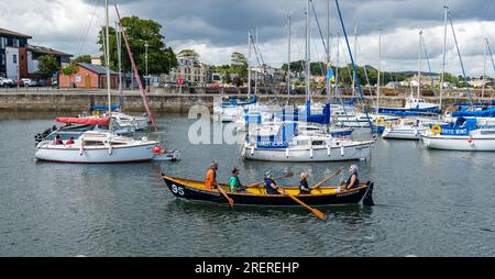 Leute in St. Ayles Ruderboote, Segel und Yachten, Fisherrow Harbour, Musselburgh, East Lothian, Schottland, UK Stockfoto