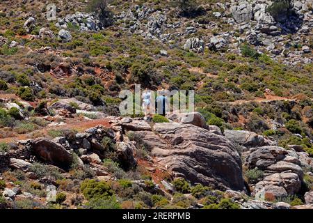 Junges Paar auf dem Weg von Livadia zum Strand von Lethra entlang des felsigen Bergpfads, Insel Tilos, Inselgruppe Dodekanes. Griechenland, Juli 2023 Stockfoto
