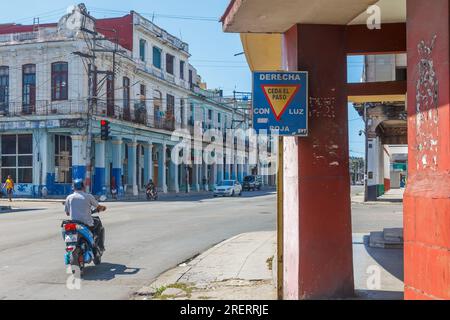 Havanna, Kuba, Ein Kubaner fährt ein E-Bike oder Fahrrad in einer Stadtstraße. Verwitterte Gebäudefassaden sind in der Ecke zu sehen. Stockfoto