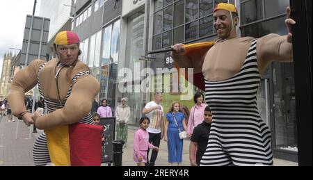 Manchester, Vereinigtes Königreich, 29. Juli 2023. Retro-Rettungsschwimmer mit altmodischen Badeanzügen und Flaggen bieten an, mit Passanten zu posieren, um Fotos und Selfies auf Deansgate neben dem Manchester Airport zu machen. Manchester Day - im Urlaub!, kostenlos, Spaß, familienfreundlich, Veranstaltungen in den Straßen des Stadtzentrums von Manchester, Großbritannien. Unterstützt von Manchester City Council, Manchester Airport Group, Biffa, The Co-op, Manchester Evening News, Wandern Sie auf dem Plank, Kingdom of Sweets, British Firefighter Challenge und Capri Beach Club. Kredit: Terry Waller/Alamy Live News Stockfoto