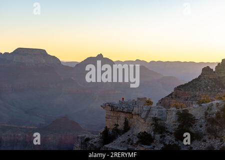 Einsame Figur am Rand des Grand Canyon bei Sonnenuntergang. Stockfoto