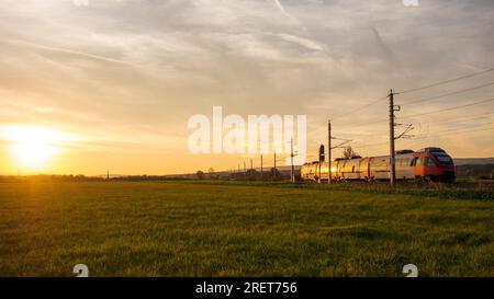 Zug fährt in das Licht der untergehenden Sonne Stockfoto