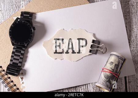 Auf hellem Hintergrund, einem braunen Notizbuch, einem schwarzen Stift und Büroklammern sowie einer gelben Karte mit dem Text EAP Employee Assistance Program Stockfoto