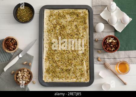 Ich mache köstliche Baklava. Backpfanne mit Teig und Zutaten auf weißem Holztisch, flach liegend Stockfoto