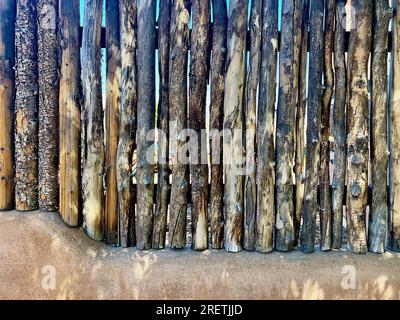 Taos, New Mexico, USA - 23. Juli 2023: Nahaufnahme eines traditionellen Holzzauns auf einer lehmwand, die im Norden von New Mexico üblich ist. Stockfoto