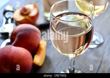 Gläser Pfirsichwein auf einem dunklen Holztisch Stockfoto