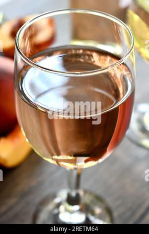 Gläser Pfirsichwein auf einem dunklen Holztisch Stockfoto