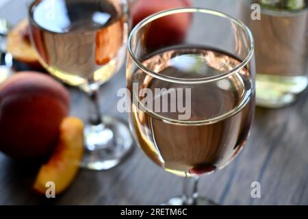 Gläser Pfirsichwein auf einem dunklen Holztisch Stockfoto