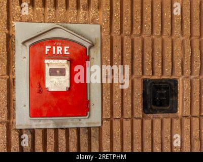 Roter Pullbox mit altem Feueralarm an der Seite eines städtischen Gebäudes in einer Stadt. Hintergrund. Schließen. Stockfoto