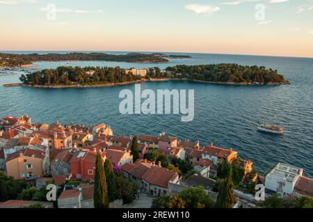 Blick auf den Sonnenuntergang über kleine mediterrane Inseln und die Dächer von Häusern in der alten istrischen Stadt Rovinj, Kroatien Stockfoto